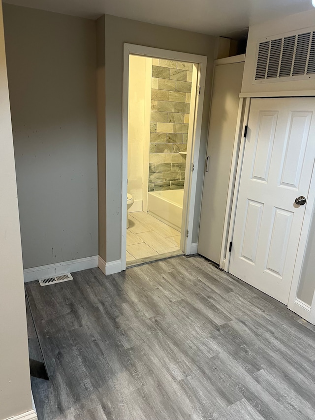 unfurnished bedroom with ensuite bath and light hardwood / wood-style floors