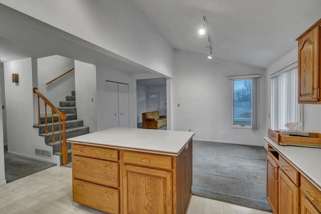 7493 S Saginaw St, New Lothrop, MI 48460 - kitchen with lofted ceiling, light colored carpet, rail lighting, light countertops, and a kitchen island