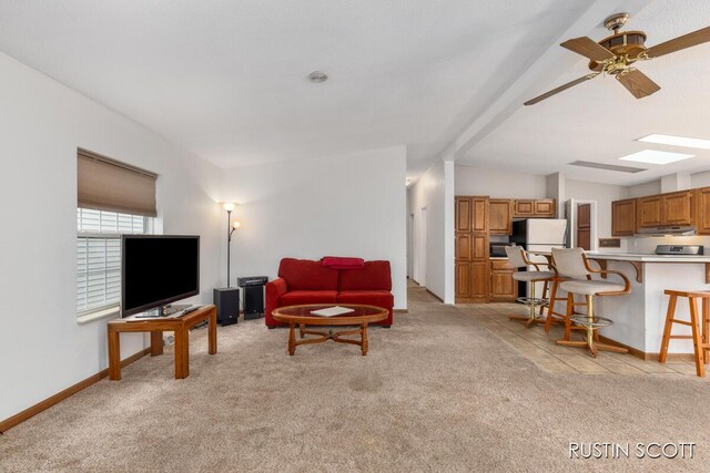 2008 Parker Dr, Wayland, MI 49348 - living room with a ceiling fan, vaulted ceiling with skylight, baseboards, and light colored carpet