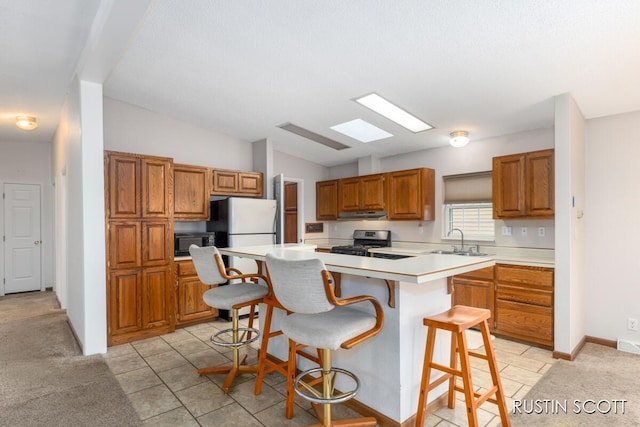 2008 Parker Dr, Wayland, MI 49348 - kitchen with light countertops, lofted ceiling with skylight, stainless steel range with gas stovetop, a sink, and brown cabinetry