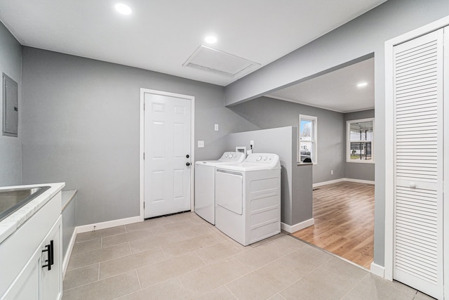 washroom with washing machine and clothes dryer, electric panel, and light hardwood / wood-style floors