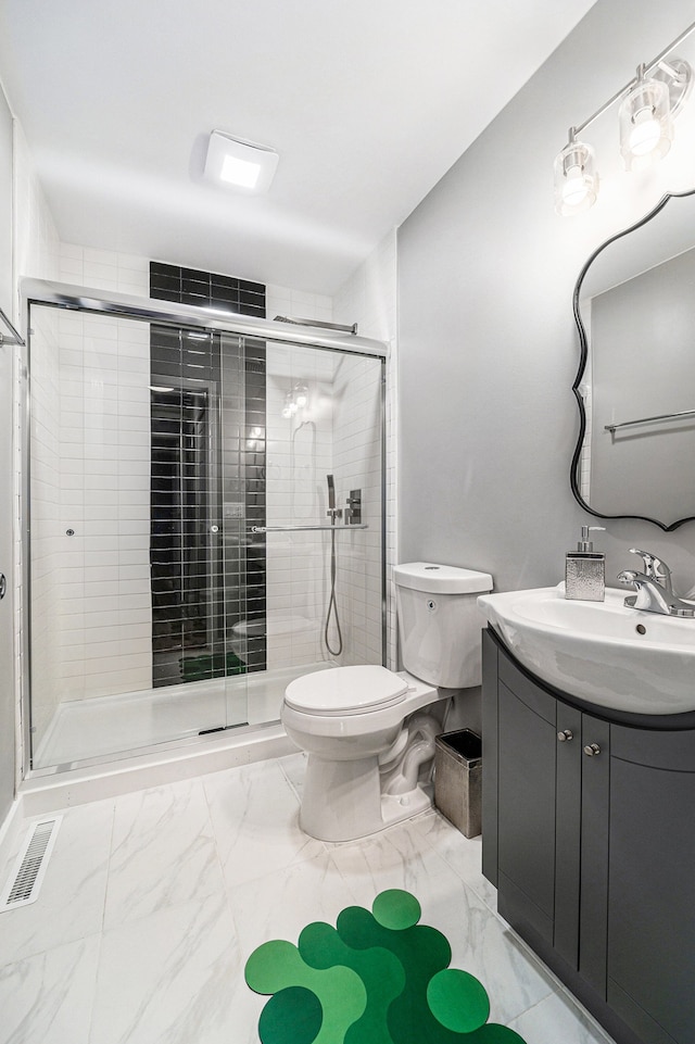 bathroom with vanity, toilet, and a shower with shower door