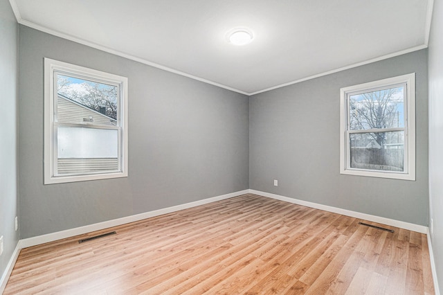 spare room featuring a healthy amount of sunlight, light hardwood / wood-style floors, and ornamental molding