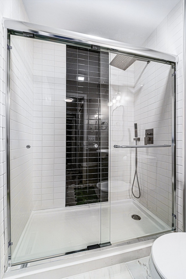 bathroom with a shower with door and toilet