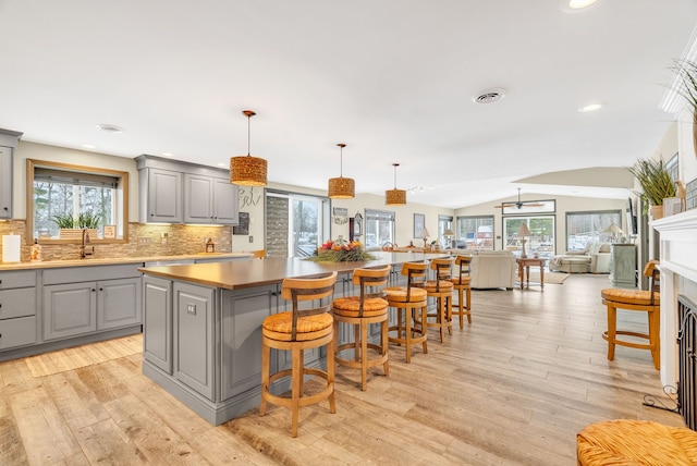 kitchen with a center island, lofted ceiling, decorative light fixtures, gray cabinets, and light wood-type flooring