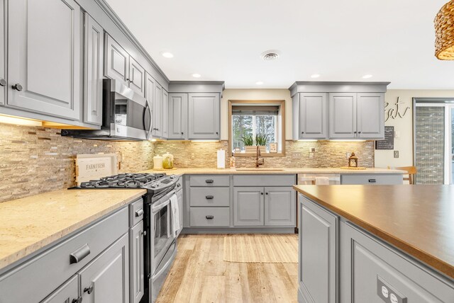 1571 Loebrich Dr, Gladwin, MI 48624 - kitchen featuring appliances with stainless steel finishes, gray cabinetry, light wood-style floors, tasteful backsplash, and recessed lighting
