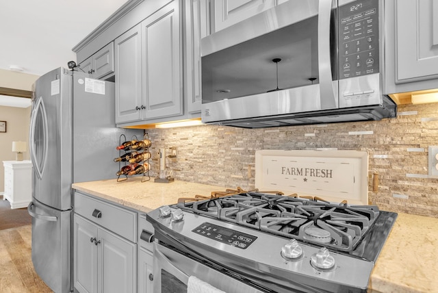 kitchen with tasteful backsplash, gray cabinetry, light hardwood / wood-style flooring, and appliances with stainless steel finishes