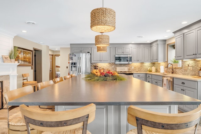 kitchen featuring stainless steel appliances, hanging light fixtures, gray cabinetry, and sink