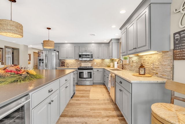 kitchen featuring gray cabinetry, hanging light fixtures, stainless steel appliances, wine cooler, and light hardwood / wood-style floors