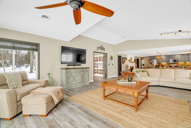 living room with ceiling fan, light hardwood / wood-style flooring, and vaulted ceiling