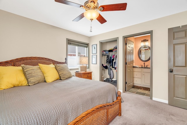 carpeted bedroom featuring ensuite bath, ceiling fan, sink, a walk in closet, and a closet