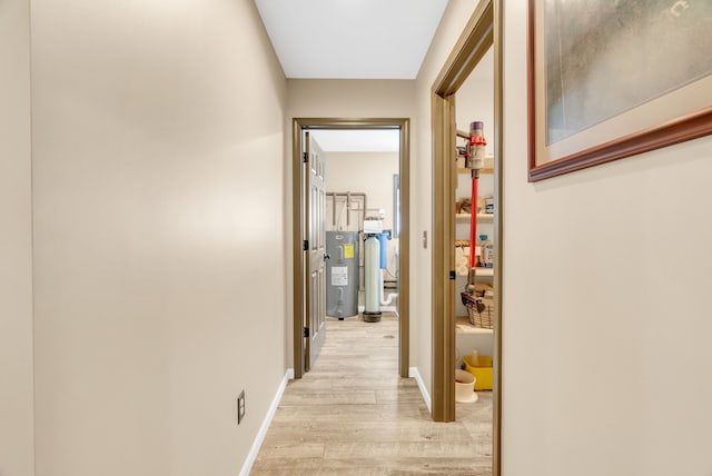 corridor with light hardwood / wood-style flooring and water heater