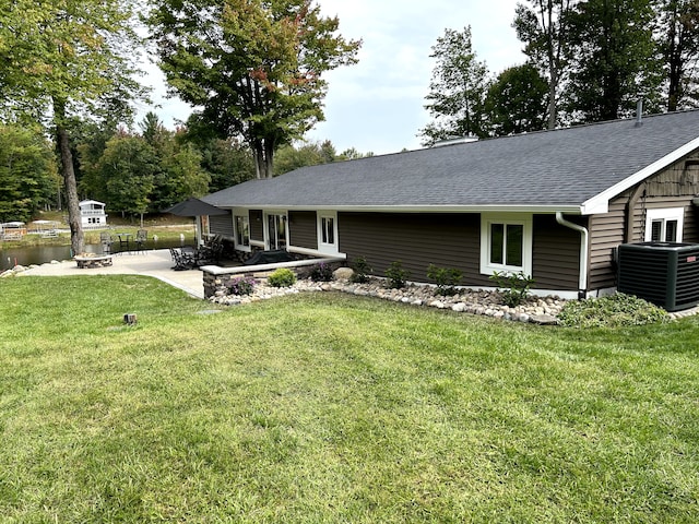 view of front of home featuring a patio, a front lawn, an outdoor fire pit, and central air condition unit