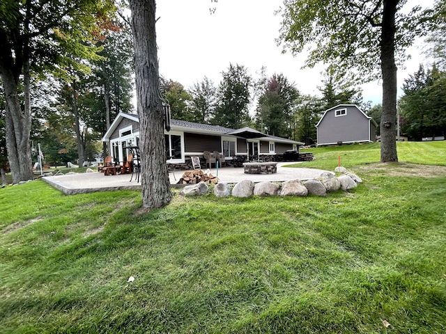 rear view of property featuring a patio, an outdoor fire pit, and a lawn