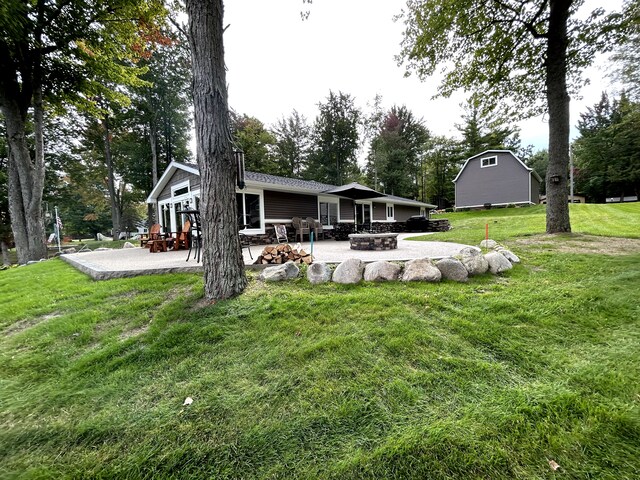 1571 Loebrich Dr, Gladwin, MI 48624 - rear view of house with a patio, a fire pit, and a lawn