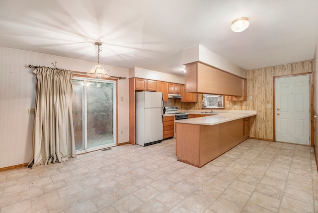 kitchen with sink, gas range oven, kitchen peninsula, white fridge, and decorative light fixtures