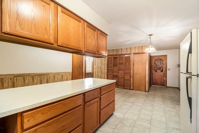 kitchen featuring wood walls, white refrigerator, and hanging light fixtures