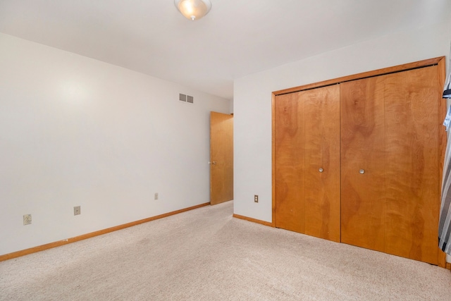 unfurnished bedroom with a closet and light colored carpet