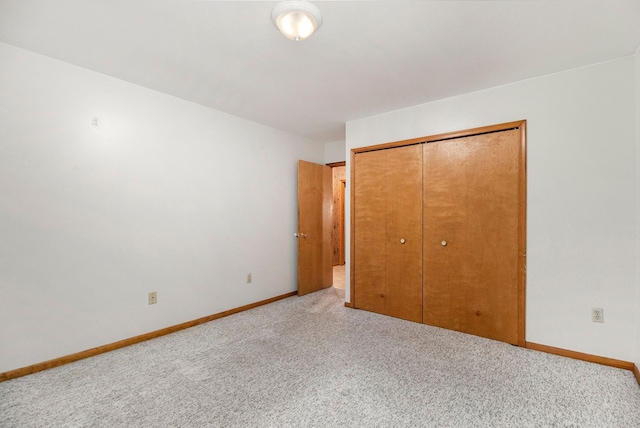 unfurnished bedroom featuring light colored carpet and a closet