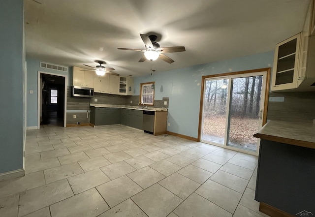 kitchen with backsplash, ceiling fan, appliances with stainless steel finishes, light tile patterned flooring, and white cabinetry