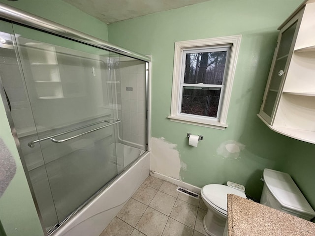 bathroom featuring tile patterned floors, combined bath / shower with glass door, and toilet