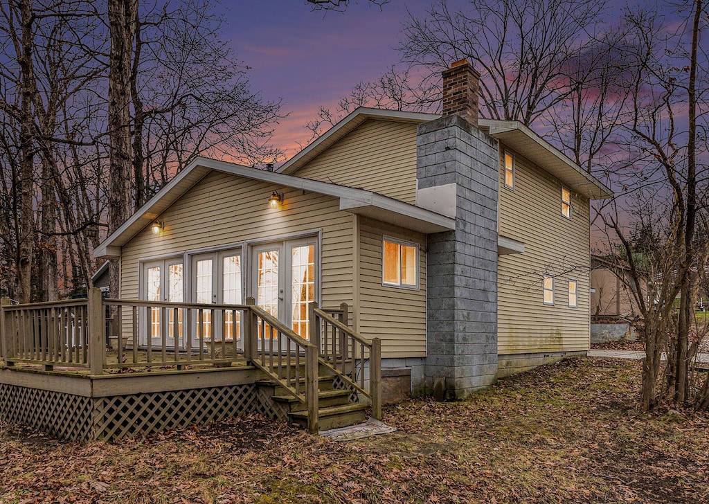 back house at dusk with a deck and french doors