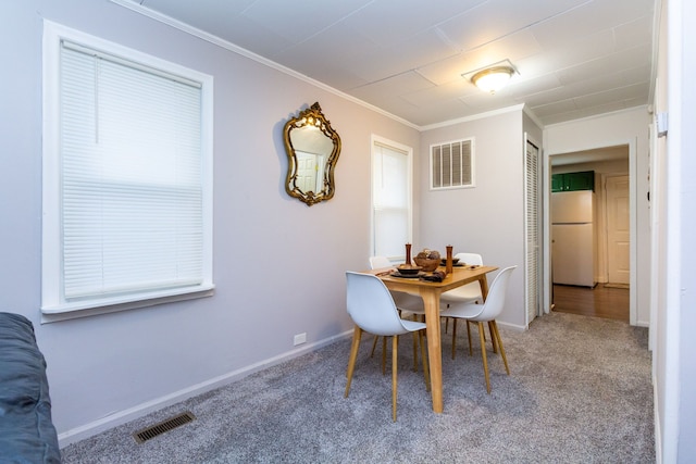 carpeted dining area featuring ornamental molding