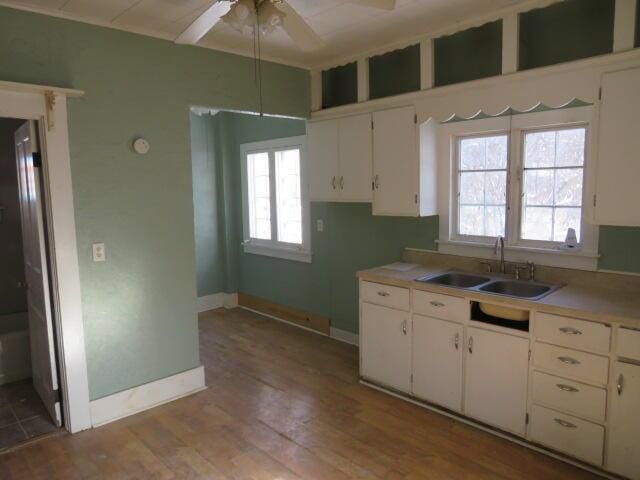 kitchen with white cabinets, a healthy amount of sunlight, light wood-type flooring, and sink
