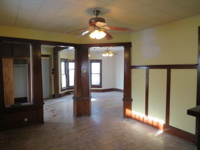 spare room featuring decorative columns and ceiling fan