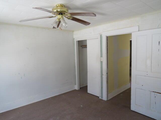 unfurnished bedroom with ceiling fan and a closet