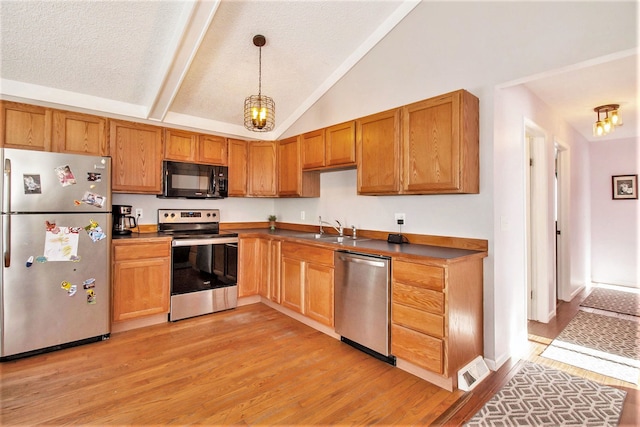 kitchen with appliances with stainless steel finishes, light wood-type flooring, a textured ceiling, sink, and pendant lighting