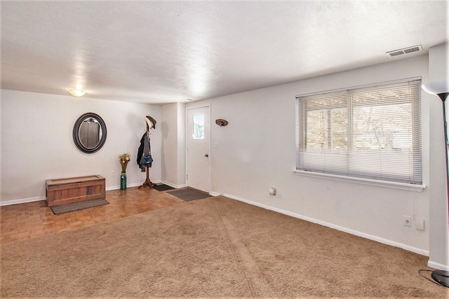 carpeted foyer entrance featuring a textured ceiling