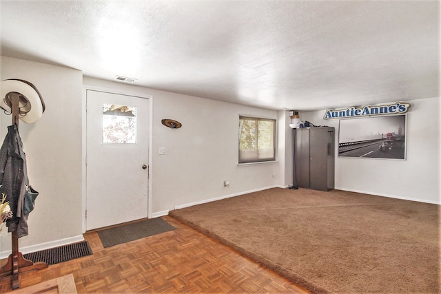 carpeted foyer with a textured ceiling