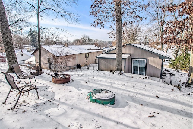 snow covered back of property with an outdoor fire pit