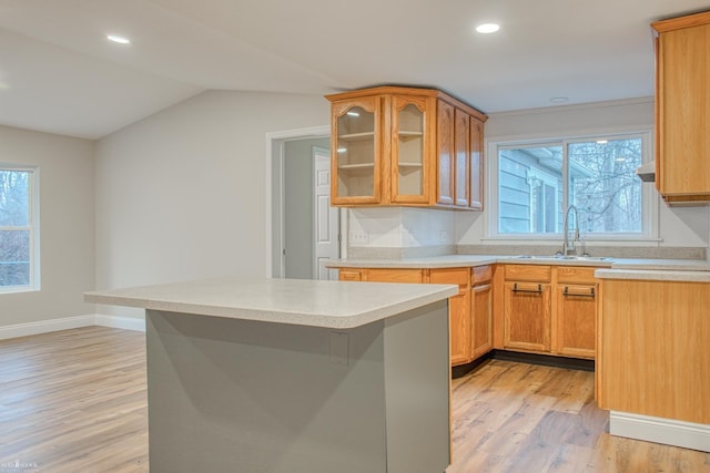 kitchen with a breakfast bar, light hardwood / wood-style flooring, lofted ceiling, and sink