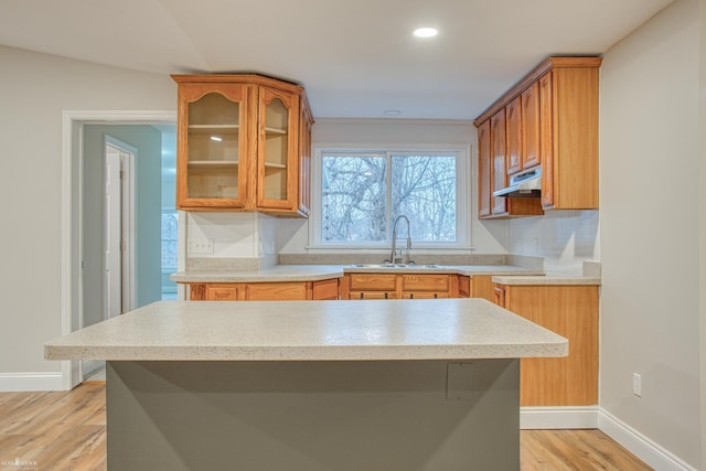 kitchen with light hardwood / wood-style floors, a kitchen island, sink, and vaulted ceiling