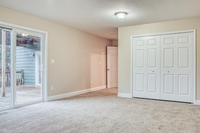 unfurnished bedroom featuring access to exterior, light carpet, and a closet