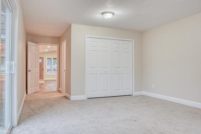 unfurnished bedroom featuring light carpet and a closet