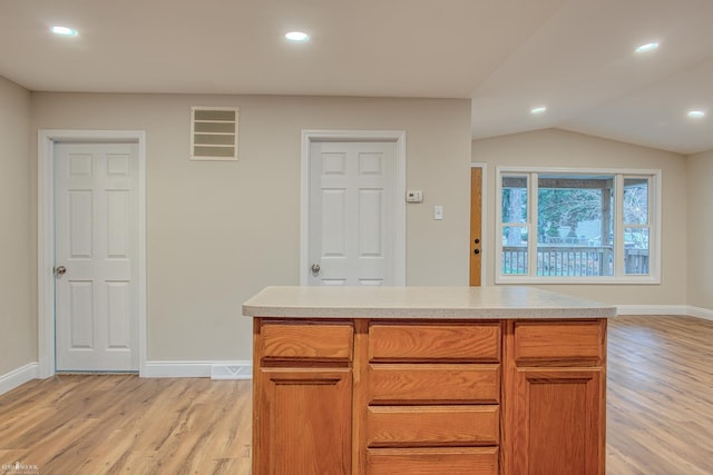 kitchen with light hardwood / wood-style flooring, a center island, and vaulted ceiling