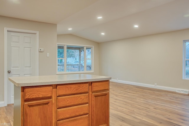 kitchen with a kitchen island, light hardwood / wood-style floors, and lofted ceiling