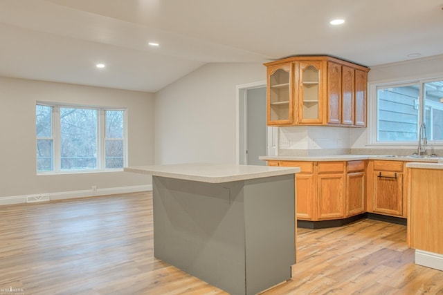 kitchen with a kitchen island, lofted ceiling, sink, and light hardwood / wood-style flooring