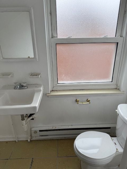 bathroom featuring tile patterned flooring, toilet, baseboard heating, and sink