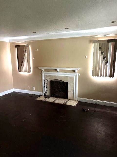 unfurnished living room with a tile fireplace, wood-type flooring, and a textured ceiling