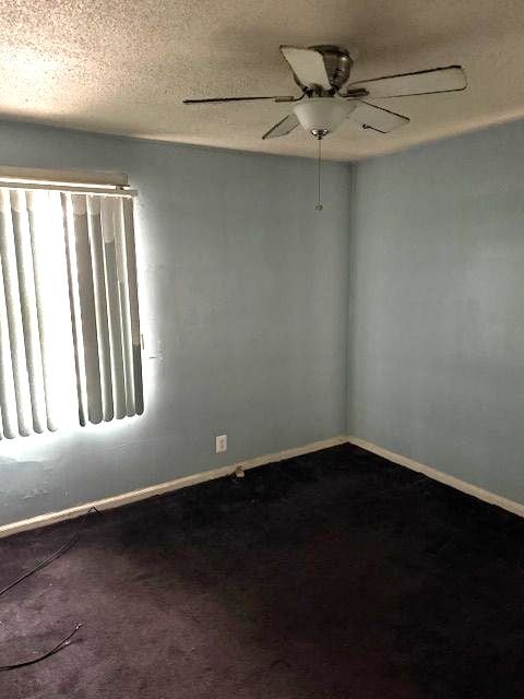 carpeted spare room featuring ceiling fan and a textured ceiling