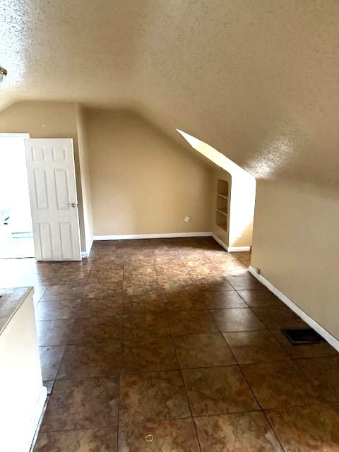 bonus room featuring vaulted ceiling and a textured ceiling