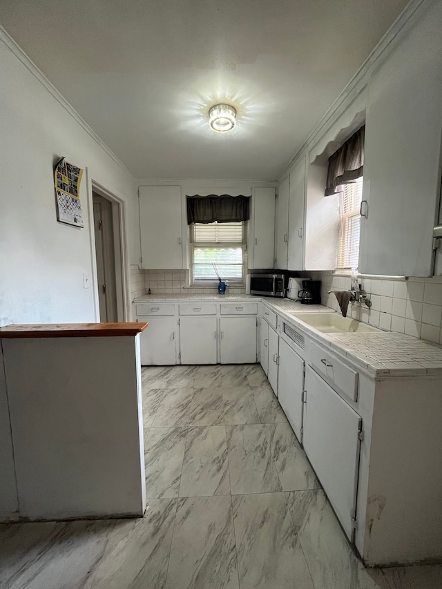 kitchen with crown molding, white cabinetry, sink, and tasteful backsplash