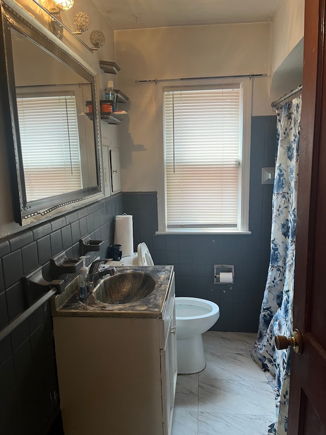 bathroom with vanity, toilet, and tile walls