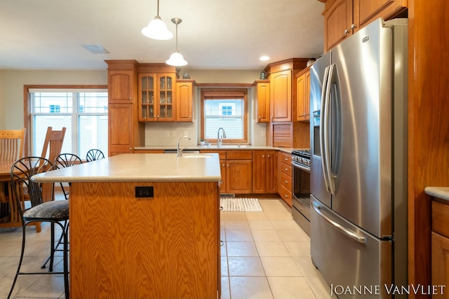 585 Crescent Dr, Holland, MI 49423 - kitchen with light countertops, appliances with stainless steel finishes, a kitchen island with sink, light tile patterned flooring, and a breakfast bar area