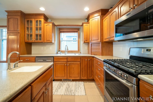 585 Crescent Dr, Holland, MI 49423 - kitchen featuring brown cabinetry, appliances with stainless steel finishes, light tile patterned floors, and a sink