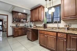 kitchen with light stone countertops, sink, light tile patterned flooring, and pendant lighting